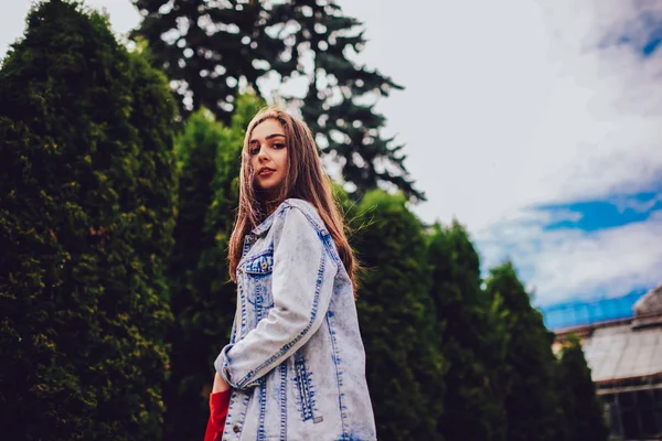 Açık havada yürürken kameraya poz esmer saçlı güzel beyaz modelinin alt görünümü. Muhteşem kadın sokakta geziniyor ceket giymiş. Trendy giyim genç kadın portresi