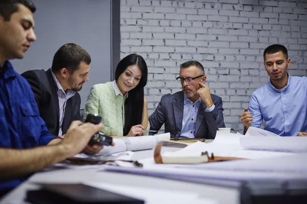 Deneyimli tasarımcıların inşaat sırasında işbirliği içinde ofis iç planlama kroki analiz. erkek ve kadın grup fikirleri tartışmak ve görüşleri çalışma işlemi sırasında paylaşım yaratıcı mimarlar