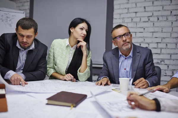 Yeni mimari görevdeki skeçler binasında oturan erkek ve dişi Mimarlar teamworking. Yaratıcı tasarımcılar mürettebatı planları yeni Office tartışırken resmi kılığına girmiş