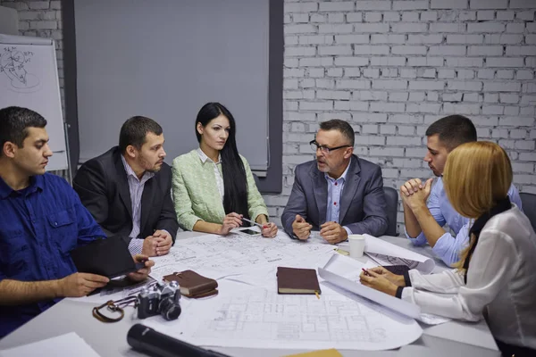 Erkek ve kadın işçiler ofiste birbirleri ile iletişim grubu. Yeni bir toplantı masada oturan projesi oluşturma oluşturma stratejisi geliştirme konusunda deneyimli profesyonellerden oluşan mürettebat