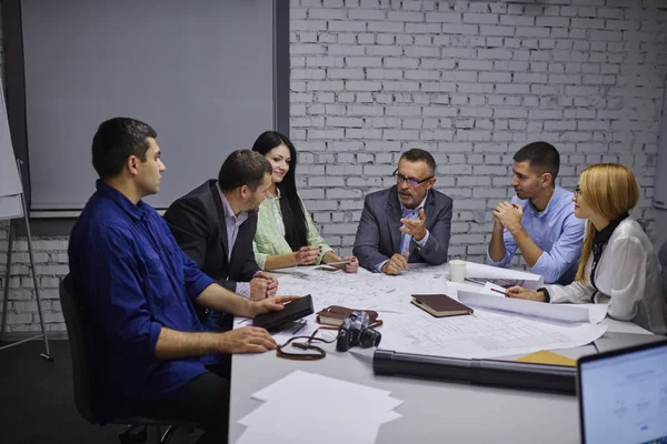 Yaratıcı ve erkek çalışan oturum beyin fırtınası sırasında sorunları çözme grubu. Profesyonel ekip deneyimli mühendis mimari çizimler ile birlikte olgun yönetmen olarak çalışıyor