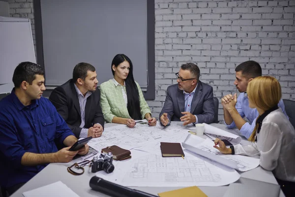 Male and female professional architects with experienced director sitting at one table during board meeting and discussing new sketches of building planning on own entrepreneurship.Mock up area