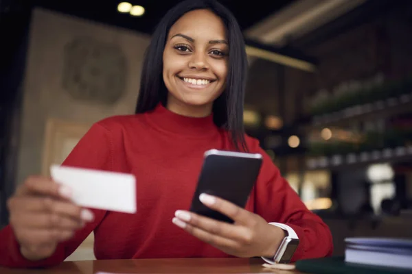 Portrait of prosperous businesswoman using visit card for contact professional economist sitting in cafe, charming young dark-skinned student happy getting card with number of company searching jo