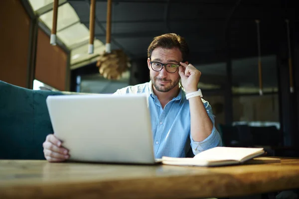 Gutaussehender Marketingexperte Blickt Skeptisch Durch Eine Brille Während Webseiten Mit — Stockfoto