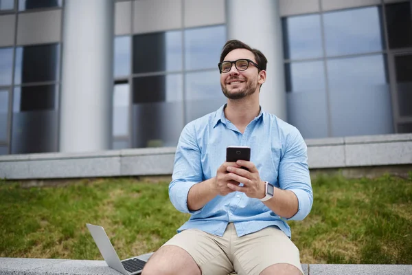 Gülümseyen yakışıklı öğrenci sosyal ağlar açık havada, 4 g bağlantı üzerinde mobil fotoğraf ve video gönderme Üniversitesi kampus içinde zevk hipster adam yeniden arkadaşımdan komik video alma gülüyor