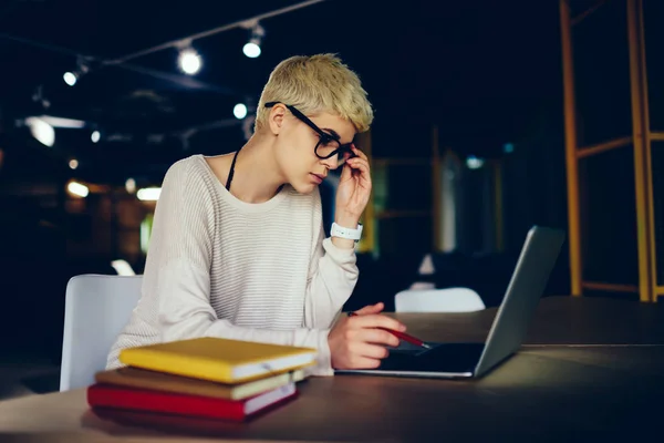 有吸引力的金发女学生在眼镜学习信息准备考试使用技术 创造性设计师做研究 同时在咖啡馆内部的新项目规划工作 — 图库照片