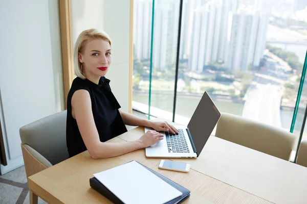 微笑的金发女郎执行经理在笔记本电脑上搜索项目计划的信息 微笑兴旺的企业妇女的肖像通过申请 Bankin 在线支付 — 图库照片