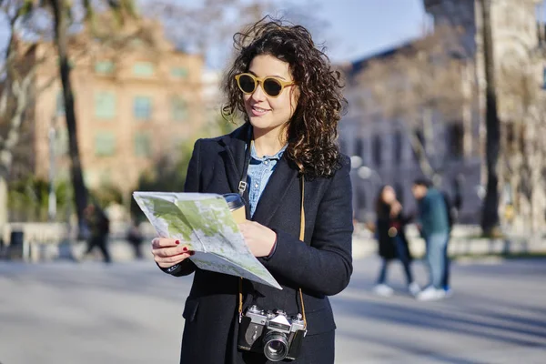 Harita ile Barcelona sokaklarda gezen şık ceket giymiş güzel pozitif kadın turist.
