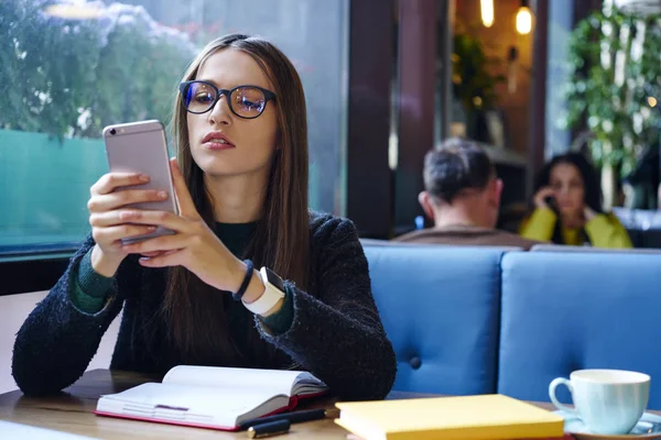 Hippi kız moda gözlük okuma telefon aygıtı sms mesajı aldı. Kahve Dükkanı iç serbest zaman sırasında oturan cep telefonunda e-posta kontrol gözlük akıllı genç kadın