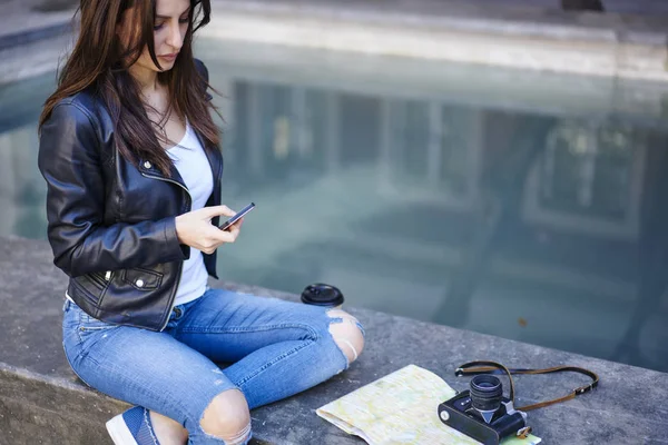 女性旅行者のローミング 魅力的な若いブルネットの女性携帯電話で市内ツアー テキスト メッセージ中に休憩でインターネットを使用してください 町の散策ルートの情報を検索を集中してください — ストック写真