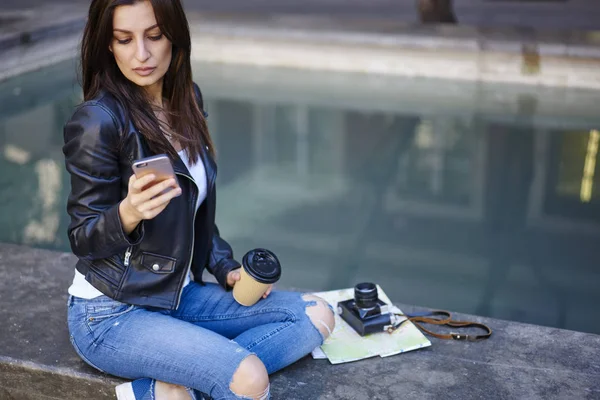 Ciddi esmer kadın seyahat blogger manifatura metin sosyal ağlar açık havada, şık giyinmiş smartphone turistik şehir turu sırasında dinlenme rotaları hakkında bilgi tarama kullanarak yayın