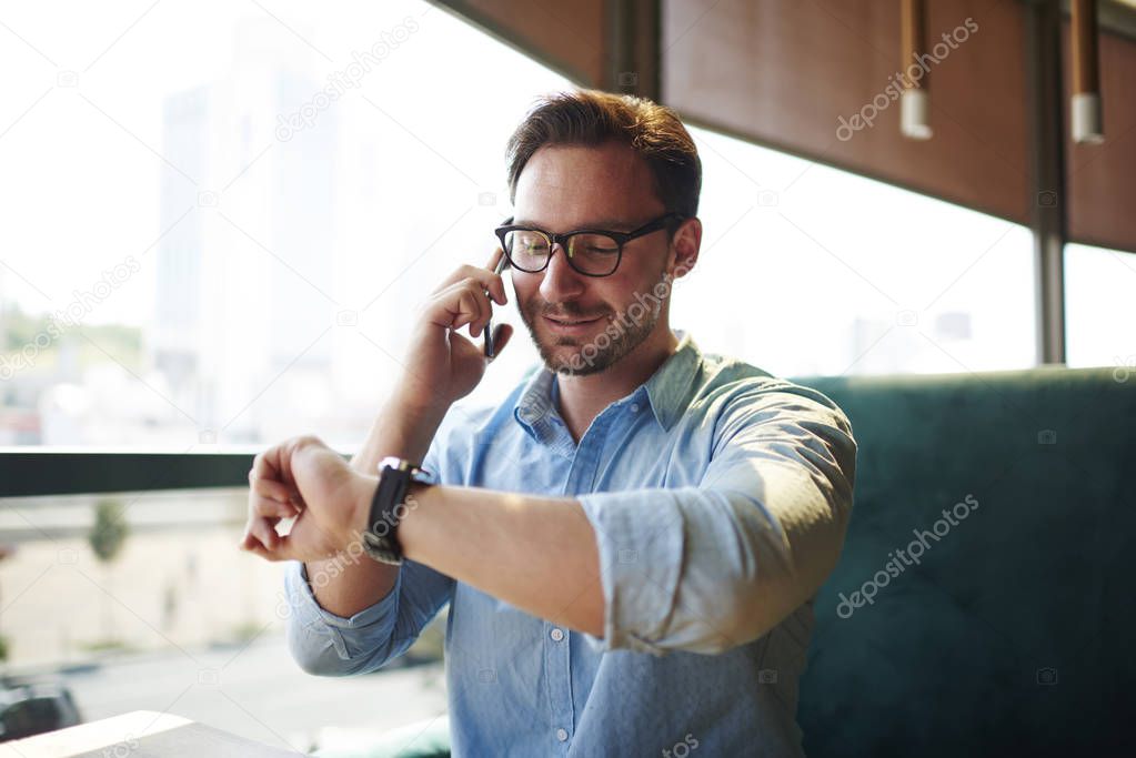 Prosperous businessman discussing with assistant working schedule during phone conversation on break, busy male entrepreneur talking on mobile with colleague managing time waiting for meeting