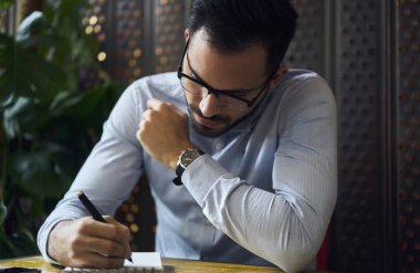 İş genç işletmeci belirterek fikirler ve yaratıcı çözüm, profesyonel tasarımcı gömlek ve gözlük kafede oturan Not Defteri'nde kroki çizim proje için strateji geliştirme konsantre