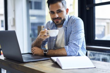 Portre pozitif bu bilgisayar yazılımı üstünde laptop bilgisayar, café atmosferde uzak iş yaparken zevk yetenekli yakışıklı metin yazarı yenilemeler yaparken geliştirici çalışma serbest olan kahve molası