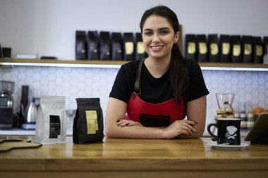 Portre pozitif genç iş kadını barista ayakta adlı bar-farklı kahve ve kapalı Cafe mola sırasında kameraya gülümseyen. Çekici kadın sahibi şık kafeteryada çalışan