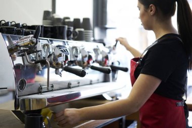 Modern kahve makinede metal profesyonel ekipman ile lezzetli espresso hazırlanması ve barista kahve dükkanında çalışan genç kadın resim kırpılmış. Kadın garson otomatik cihaz ayakta