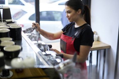 Kadın barista kahve kafeteryada işgal ile memnun yapma süreci zevk deneyimli. Cafe güzel çalışan istemciler profesyonel ekipman üzerinde sipariş hazırlama personeli üniformalı giyinmiş