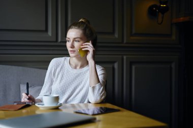 Düşünceli profesyonel gazeteci iş fikirleri tartışmak ve planlama tabl oturma çalışma süreci sırasında uygulamaya kullanarak cep üzerinden arkadaşlarınızla iletişim rahat kıyafet giymiş