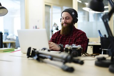 Dizüstü bilgisayarda uygulama kullanmasına ve müzik yaratmak pozitif erkek composition kulaklık aracılığıyla yaptı. Favori şarkı listesi coworking içinde oturan dinleme serin şapkalı sakallı adam