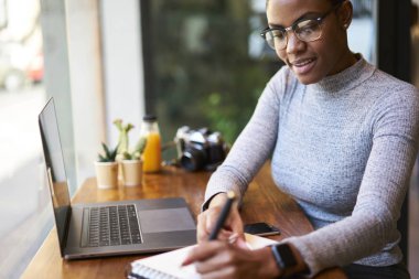 Çekici afro Amerikalı tasarımcı kahve dükkanı, yetenekli freelancer kafe iç çalışma süreci zevk pazarlama araştırma yapma zaman harcama ise proje planlama kroki oluşturma gülümseyen