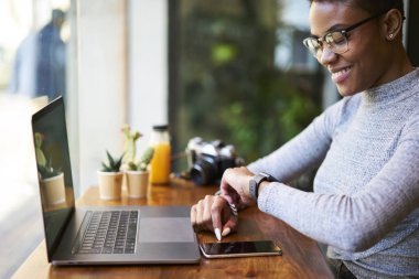 Neşeli afro Amerikan kadın web tasarımcısı önce tarihler serbest dizüstü bilgisayar ve wifi kullanarak kafe Ardiles oturan online para kazanmak zamanında bitirme başarılı proje ile memnun