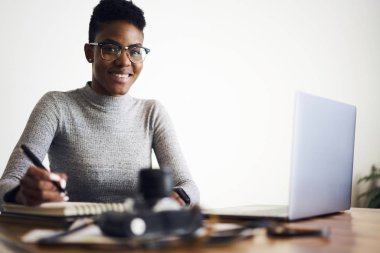 Promosyon beyaz zemin üzerine oturan mali rapor planlama ofisi coworking mesafe iş yapma işgal çekici neşeli afro Amerikan buinesswoman bardaklarda portresi memnun