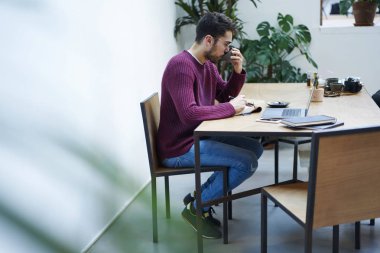 Genç erkek öğrenci üniversite iç kahve molası sırasında bilgisayar üzerinden sınıfları için hazırlanıyor gözlük. Kısa mesaj reklam için yer alan kopyalayın. Adam serbest meslek webinar üstünde laptop