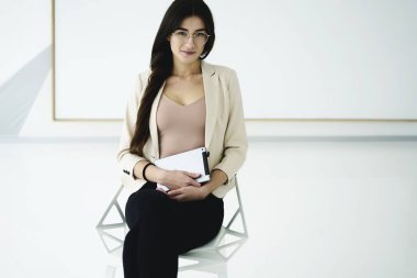 Zarif resmi Sevimli Esmer iş kadın portresi giymek ofiste kapalı kamera, trendy gözlük ile iş memnun içinde çekici gurur kadın Ceo bakarak touchpad ile oturuyor.