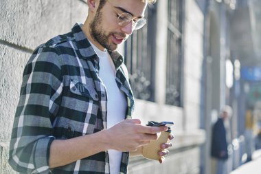 İyi görünümlü şık gözlükler online mağazasında rezervasyon ve smartphone ile ödeme yapma kablosuz internet'e bağlı öğrenci yoğunlaştı. Sakallı adam açık havada duran süre teknolojisini kullanarak