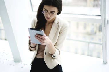 Dalgın esmer işkadını Eyewear Finansal Haberler dijital tablet, touchpad üzerinde çevrimiçi işlem yapma banka hesabınızı kontrol deneyimli kadın girişimci'ı okuma