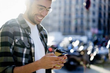 Mutlu genç hipster adam akıllı komik video izliyor bağlı 4g yüksek hızlı internet şehirde gezinme sırasında. Cep telefonu uygulaması üzerinde mesajý okurken gülmekten olumlu erkek