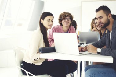 Neşeli ve erkek öğrenciler ilginç eğitim ders ile her diğer, beyin fırtınası ve işbirliği alanı coworking içinde zevk meslektaşları iletişim teknolojisini kullanarak