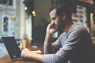 Cep telefonu üzerinden meslektaşı ile iletişim sırasında dizüstü bilgisayar aygıtla sahte alanı reklam web sayfanızın kafede çalışan rahat kıyafet giymiş genç yakışıklı grafik tasarımcı