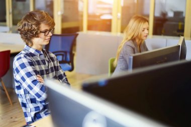 Optik gözlük eğitim sunum dijital yüksek olarak bağlanan bilgisayar üzerinde izlerken dalgın hipster adam hızda internet alan coworking içinde oturuyor. Monitörde arayan erkek öğrenci konsantre