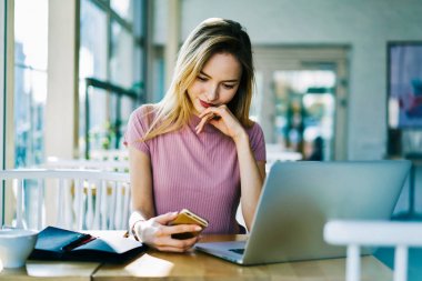 Sarışın kız öğrenci smartphone sosyal ağlarda dizüstü bilgisayarda, profesyonel Yöneticisi alış online ödeme yapmadan rapor oluşturulurken sohbet üzerinde e-posta kutusunu kontrol konsantre