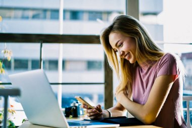 Çekici Yöneticisi kafe iç kontrol e-posta kutusunda smartphone alıcı iyi reklam teklif üzerine oturan; neşeli sarışın öğrenci paylaşım multimedya dosyaları mobil dizüstü bilgisayar ile senkronize