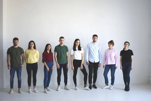 Full length portrait of casual dressed group of young people posing on white wall background with copy space area for your advertise or promotional content. Team, students