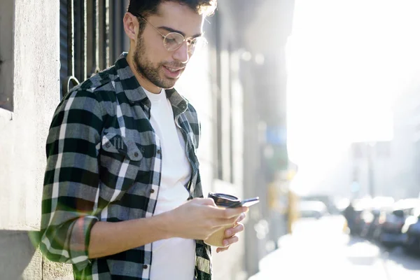 英俊漂亮的男性短信反馈在论坛上的电话连接到4G 互联网在城市周围漫步 年轻的时髦家伙在眼镜步行在城市设置户外小工具 — 图库照片