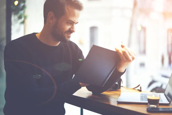 Gutaussehender Bärtiger Coffeeshop Besitzer Sitzt Mit Laptop Und Überprüft Notizbuch — Stockfoto