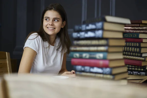 Uśmiechający Się Sprytny Student Siedzi Wielu Książek Edukacyjnych Przy Stole — Zdjęcie stockowe