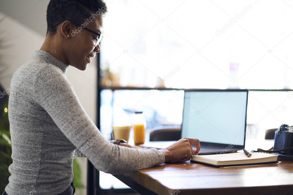 Concentrated afro american freelancer planning strategy of working task making remote job in good mood,prosperous businesswoman using laptop computer with mock up screen for browsing information