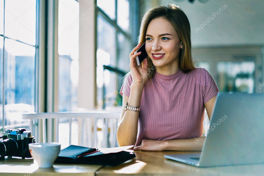Charming blonde female administrative manager having phone conversation talking about business planning, professional attractive editor making booking calling to service satisfied with good offer