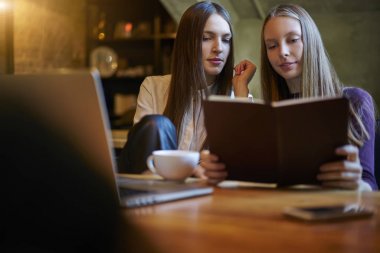 Eğitim kitabı okuma ve birlikte yaklaşan sınavlar için kablosuz 4 g bağlanmanızı modern dizüstü bilgisayar aygıt, şık coworking uzayda oturan hazırlama akıllı kız öğrenci internet