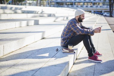Reklam sosyal ağ video izlemek için kopyalama alanı alanı oturan rahat kıyafet giymiş genç hipster adam gülümsüyor, yakışıklı erkek turist bloglama telefonu üzerinden bağlı 4 g için Internet