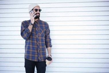 Şık giyim ayakta beyaz promosyon arka planda telefon, gezici bağlantısı kullanarak arama gitmek için gezinme kahve ile hafta sonları zevk genç erkek turist konuşurken kendinden emin sakallı adam