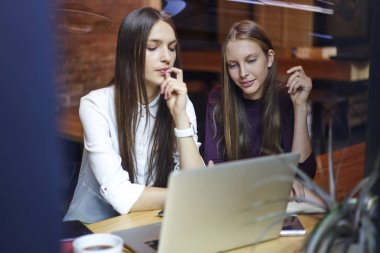 Dalgın gençler için kablosuz 4 g bağlanmanızı modern dizüstü bilgisayar aygıt online video izleme internet şık coworking uzayda oturuyor. Genç kadın kahve dükkanı iç macbook bilgisayar öğrenim