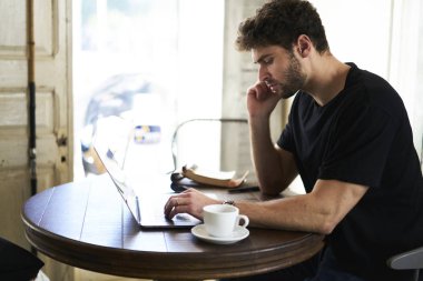 Meşgul girişimci meslektaşım kafede oturan ve uzaktan çalışma modern telefon aracılığıyla iş onarma sakallı. Laptop klavye üzerinde metin yazarken cep üzerinde söz yazarı