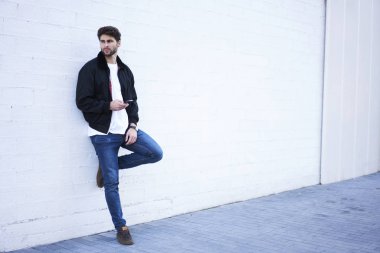 Modern telefon yüksek hızlı 4 g internet hposing reklam metin mesajınız için promosyon arka plan beyaz duvarının yakınında kamerasına bağlanma şık yakışıklı delikanlı. Kopyalama alanı alanı