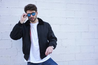 Emin yakışıklı erkek yarım uzunluk portre boş zaman zaman ayakta promosyon içerik için kopya alanı ile renkli arka plan karşı tadını çıkarırken kameraya bakarak moda giyim giyinmiş