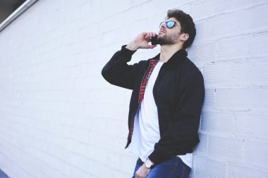 Sakallı ciddi hipster adam telefon arkadaş grubu için 4 g bağlı Smartphone cep telefonu ile konuşmayı rahat kıyafet giymiş. Modern gezinme sırasında hücresel konuşmak iyi görünümlü kendinden emin bir adam
